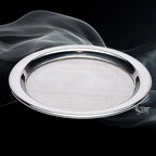 Tamis rond en métal argenté avec grille fine, présenté en perspective sur fond noir avec volutes de fumée.