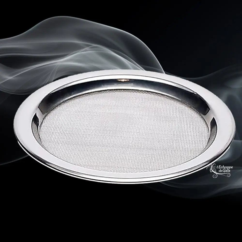 Tamis rond en métal argenté avec grille fine, présenté en perspective sur fond noir avec volutes de fumée.
