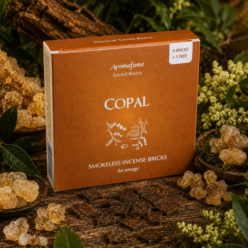 Boîte ambrée d'encens Aromafume Sacred Resins Copal entourée de morceaux de résine ambrée, avec des briques d'encens carrées étalées sur une table en bois.
