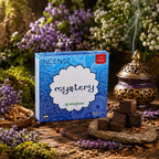 Boîte bleue d'encens Aromafume Mystery posée au milieu de fleurs de lavande et de copeaux de santal, avec des briques d'encens carrées et un brûleur exotique.