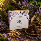 Boîte d'encens Aromafume Palo Santo & Lavender entourée de brins de lavande et de morceaux de Palo Santo, avec des briques d'encens carrées et un diffuseur ciselé.