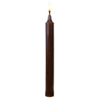 Bougie teintée dans la masse marron chocolat, fine et élancée, allumée sur fond blanc pour mettre en valeur sa couleur chaude.