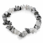 Un bracelet baroque en pierres naturelles de cristal de roche tourmaline, composé de petits éclats polis mêlant transparence et inclusions noires, montés sur un fil élastique, présenté sur un fond blanc.