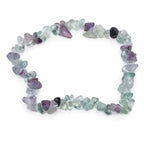 Un bracelet baroque en pierres naturelles de fluorite, composé de petits éclats polis aux nuances variées de violet, vert et translucide montés sur un fil élastique, présenté sur un fond blanc.