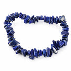 Un bracelet baroque en pierres naturelles de lapis-lazuli, composé de petits éclats polis d'un bleu profond intense montés sur un fil élastique, présenté sur un fond blanc.
