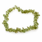 Bracelet en péridot aux éclats vert olive translucides, disposé en cercle sur un fond blanc avec reflet.