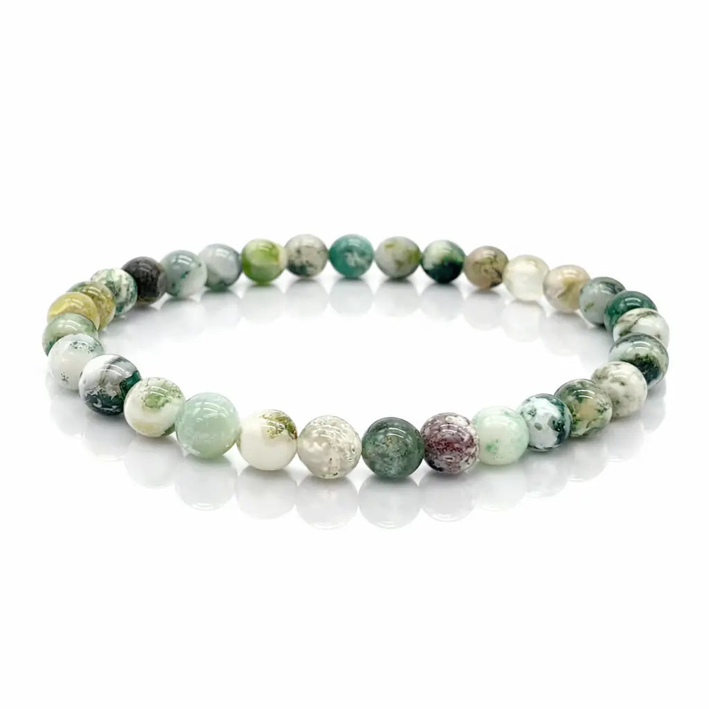 Bracelet élastique en perles rondes vertes et blanches, aspect marbré, disposé en cercle sur fond clair