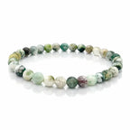 Bracelet élastique en perles rondes vertes et blanches, aspect marbré, disposé en cercle sur fond clair