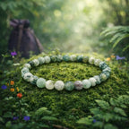 Bracelet de perles rondes et lisses en agate arbre aux motifs de feuillages verts et blancs, délicatement posé sur une mousse forestière vibrante.