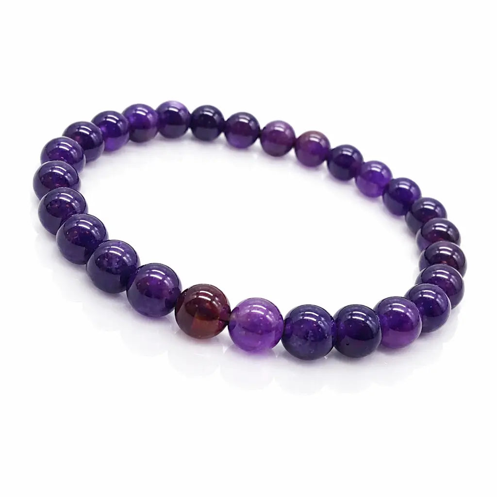 Bracelet en perles rondes d'améthyste violet foncé polies sur un fond blanc épuré.