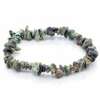 Bracelet élastique composé de petites pierres baroques aux nuances de vert, bleu et brun sur fond blanc.