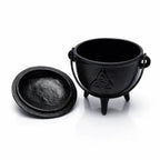 Petit chaudron en fonte noire avec symbole Triquetra gravé, couvercle posé à côté sur fond blanc.
