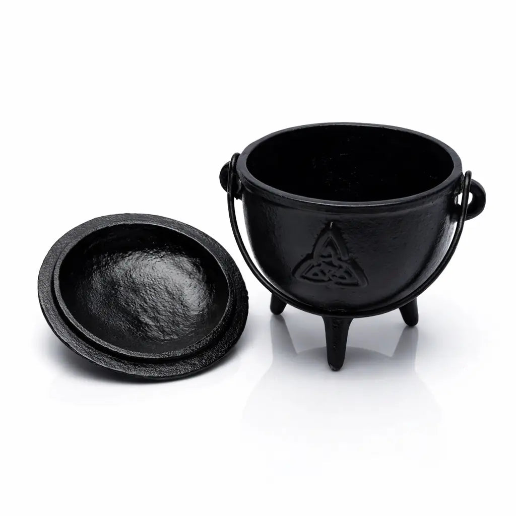 Petit chaudron en fonte noire avec symbole Triquetra gravé, couvercle posé à côté sur fond blanc.