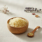 Coupelle en bois remplie de grains d’encens mastic jaune pâle avec petite cuillère sur tissu clair.
