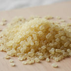 Gros plan sur des grains de résine d’encens mastic jaune pâle en tas sur surface en bois.
