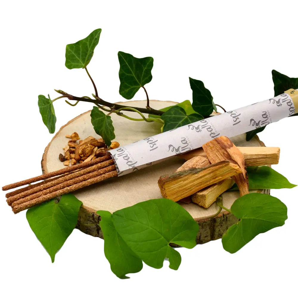 Composition d'encens Ispalla avec bâtonnets, morceaux de bois de Palo Santo et feuilles de lierre sur un socle en bois.