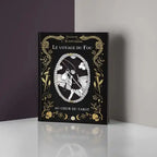 Livre Le Voyage du Fou posé debout, couverture noire avec ornements dorés et illustration du Fou, sur fond gris.