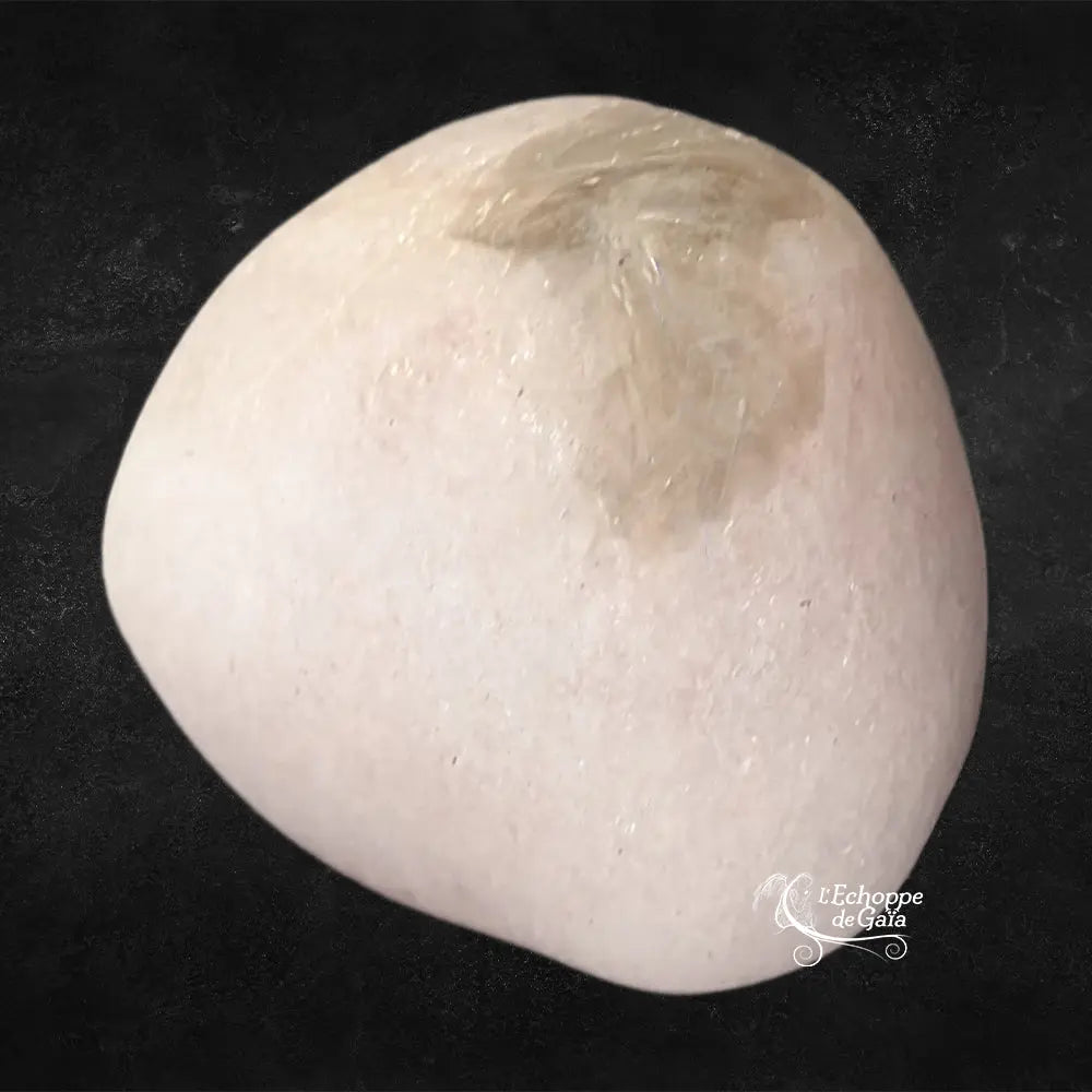 Pierre de morganite polie, présentant une teinte crème presque blanche avec une zone texturée légèrement plus sombre, photographiée sur un fond noir.
