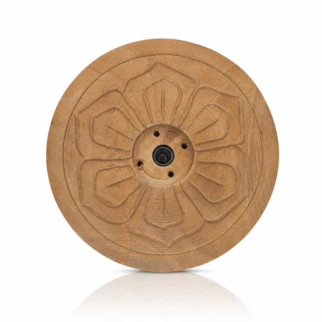 Un porte-encens rond en bois sculpté d'un motif de fleur, doté de plusieurs trous centraux et présenté sur fond blanc.