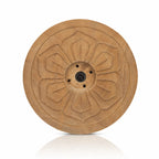 Un porte-encens rond en bois sculpté d'un motif de fleur, doté de plusieurs trous centraux et présenté sur fond blanc.