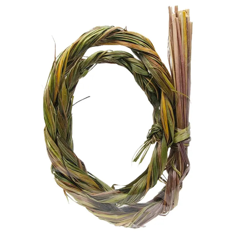 Tresse purificatrice de foin d’odeur (sweet grass) nouée en cercle, aux brins vert-doré légèrement torsadés, extrémité en petit faisceau lié sur le côté droit, présentée seule sur fond blanc pour une mise en avant produit nette et épurée.