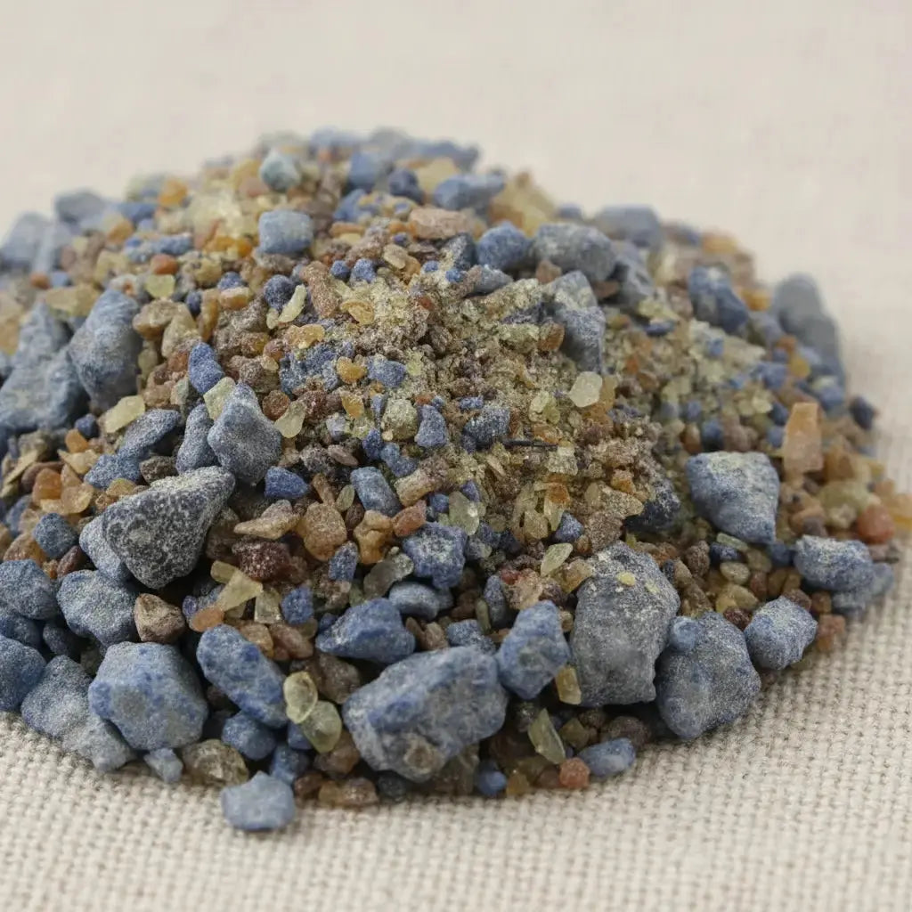 Gros plan sur un monticule de morceaux de résine d'encens Abbé Julio, mélange de gros grains bleu-gris et de petits morceaux d'ambre et de résine claire.