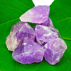 Bloc d'améthyste brute présentant des cristaux pointus aux nuances violettes intenses sur une base de roche grise naturelle, posé sur un fond blanc.