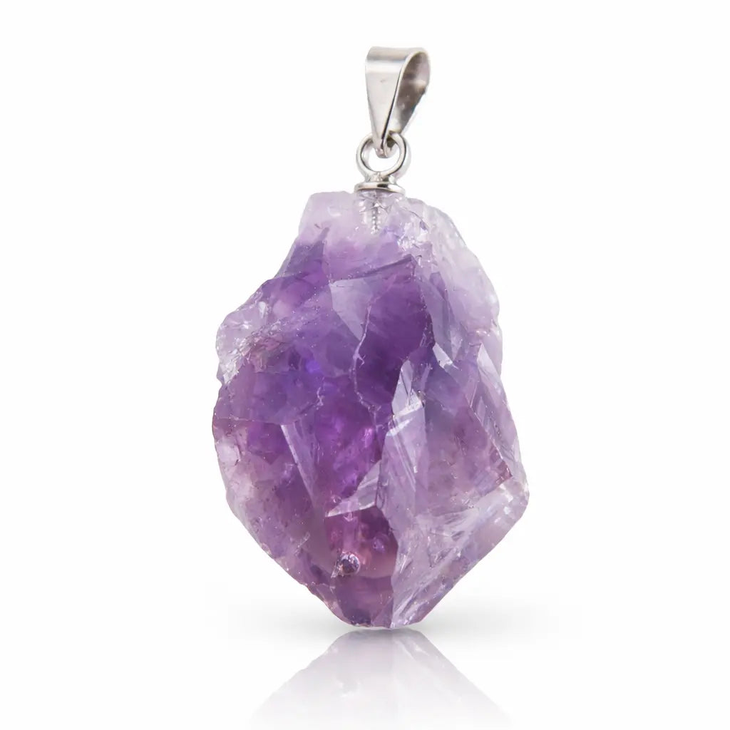 Un pendentif en améthyste brute d'un violet intense avec des facettes cristallines naturelles, surmonté d'une bélière en métal argenté, présenté avec son reflet sur un fond blanc.