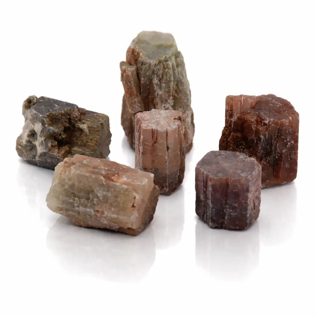 Une sélection de cristaux d'aragonite maclée aux formes prismatiques naturelles et aux nuances terreuses (brun, ocre, gris), présentés en groupe sur un fond blanc avec reflets.