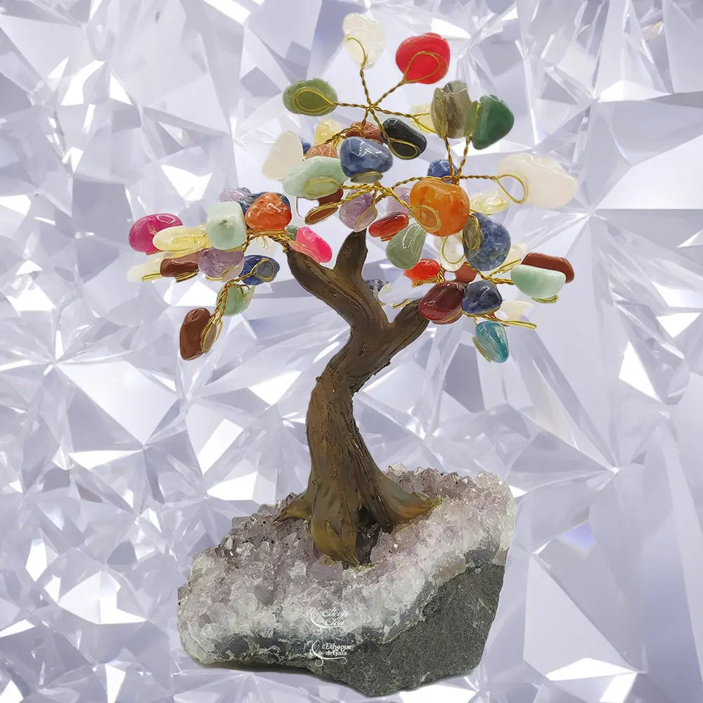 Arbre du bonheur aux feuilles en pierres naturelles multicolores et branches dorées, monté sur un socle d'améthyste brute, devant un fond blanc géométrique.