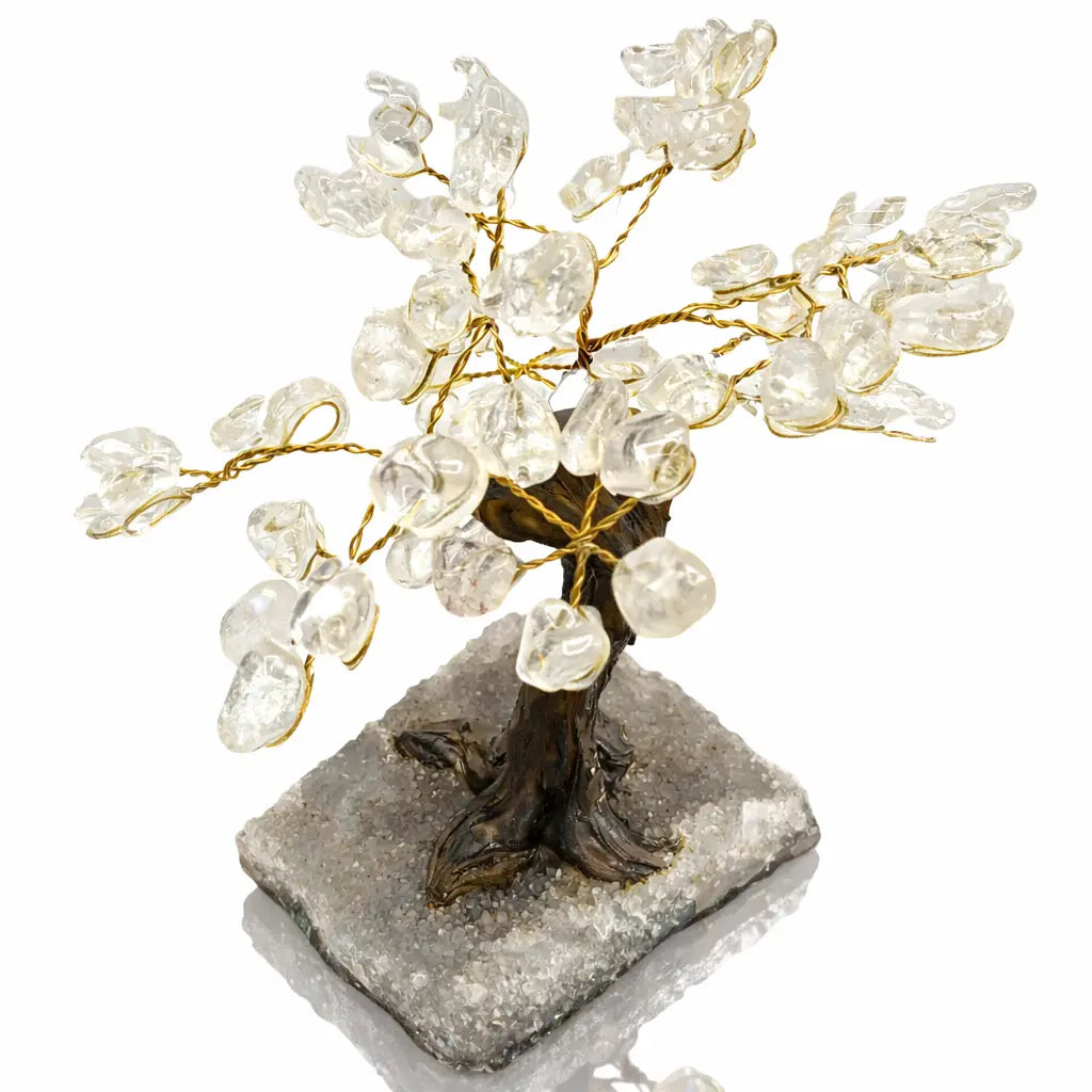 Un arbre du bonheur décoratif aux feuilles en pierres de cristal de roche et branches dorées, s'élevant d'un socle rectangulaire recouvert de petits cristaux, présenté sur un fond blanc.
