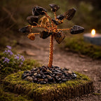 Arbre de vie miniature aux feuilles d'oeil de tigre sombres et dorées, tronc en cuivre torsadé sur un socle de petits galets noirs et bruns.