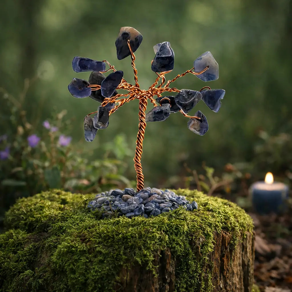 Arbre de vie miniature aux feuilles en éclats de sodalite bleu nuit veinés de blanc, sur un tronc de cuivre torsadé posé sur une souche forestière.
