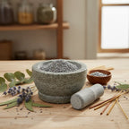 Grains d'encens de résine Argent (gris métallisé) dans un mortier en granit gris avec pilon, entouré de brins de lavande, de feuilles d'eucalyptus et de bâtonnets d'encens.