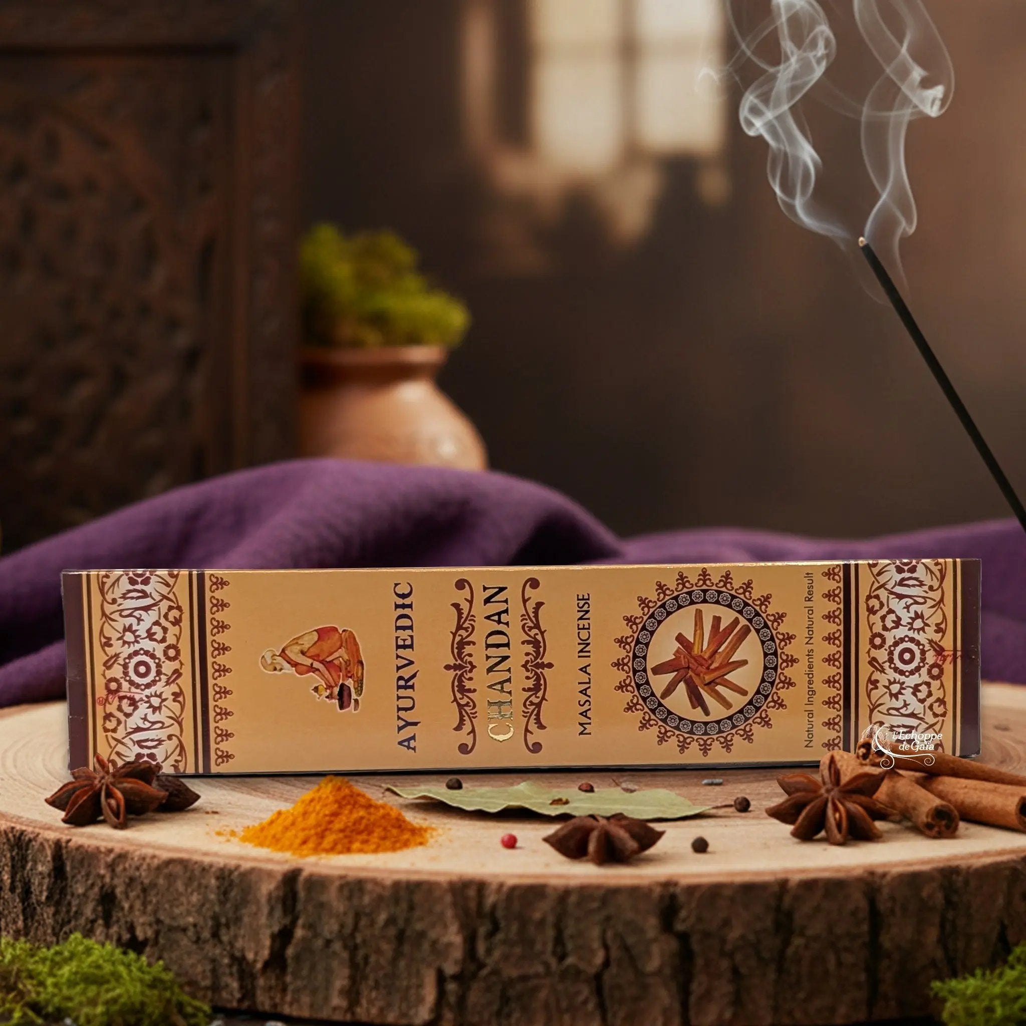 Boîte d'encens "Ayurvedic Chandan Masala" sur une rondelle de bois, avec épices et encens fumant.