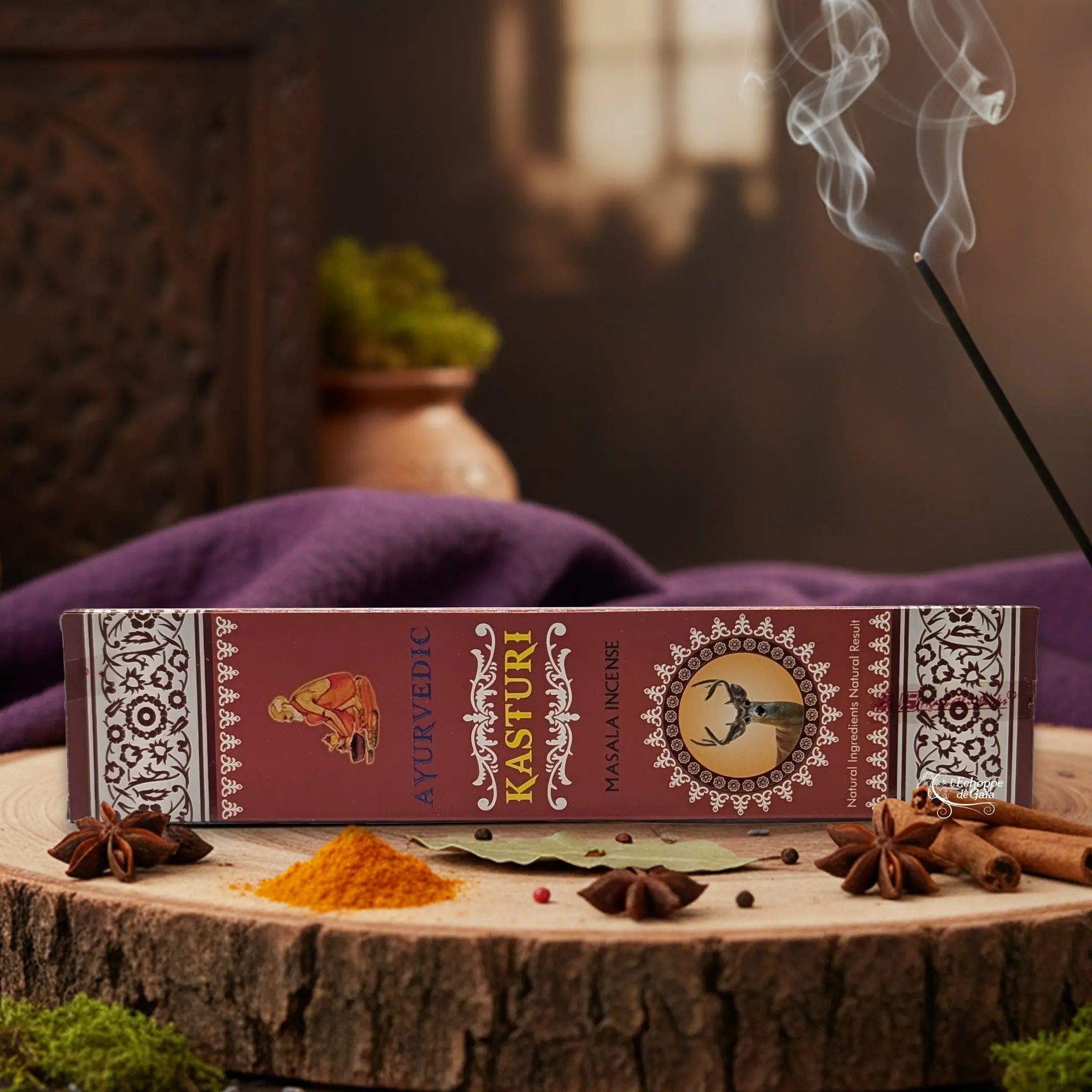 Boîte d'encens "Ayurvedic Kasturi Masala" sur une rondelle de bois, avec épices et encens fumant.