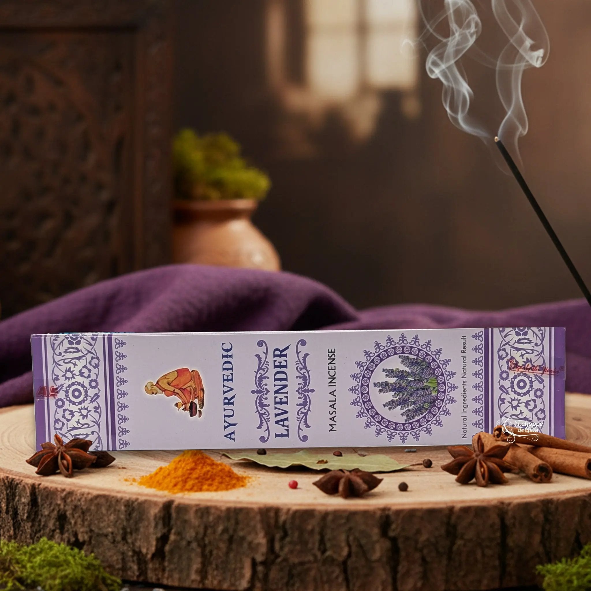 Boîte d'encens "Ayurvedic Lavender Masala" sur une rondelle de bois, avec épices et encens fumant.
