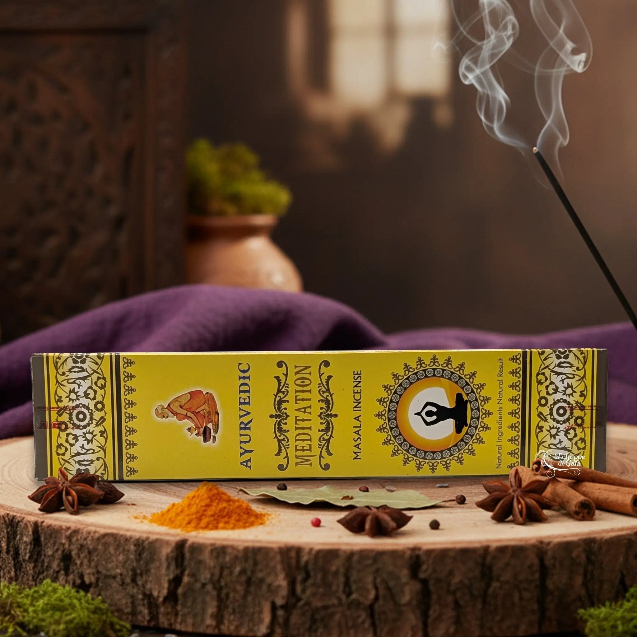Boîte d'encens "Ayurvedic Meditation Masala" sur une rondelle de bois, avec épices et encens fumant.