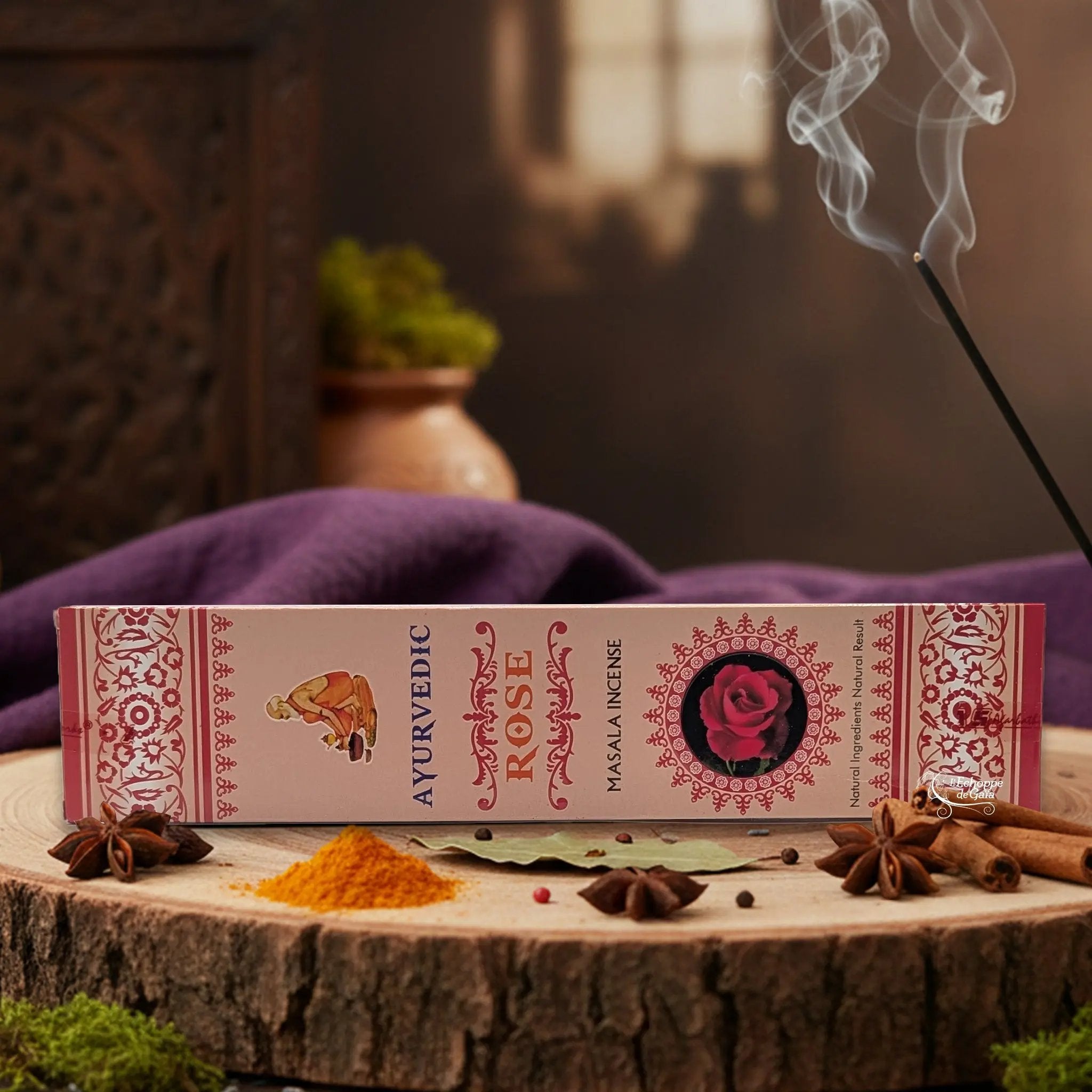 Boîte d'encens "Ayurvedic Rose Masala" sur une rondelle de bois, avec épices et encens fumant.