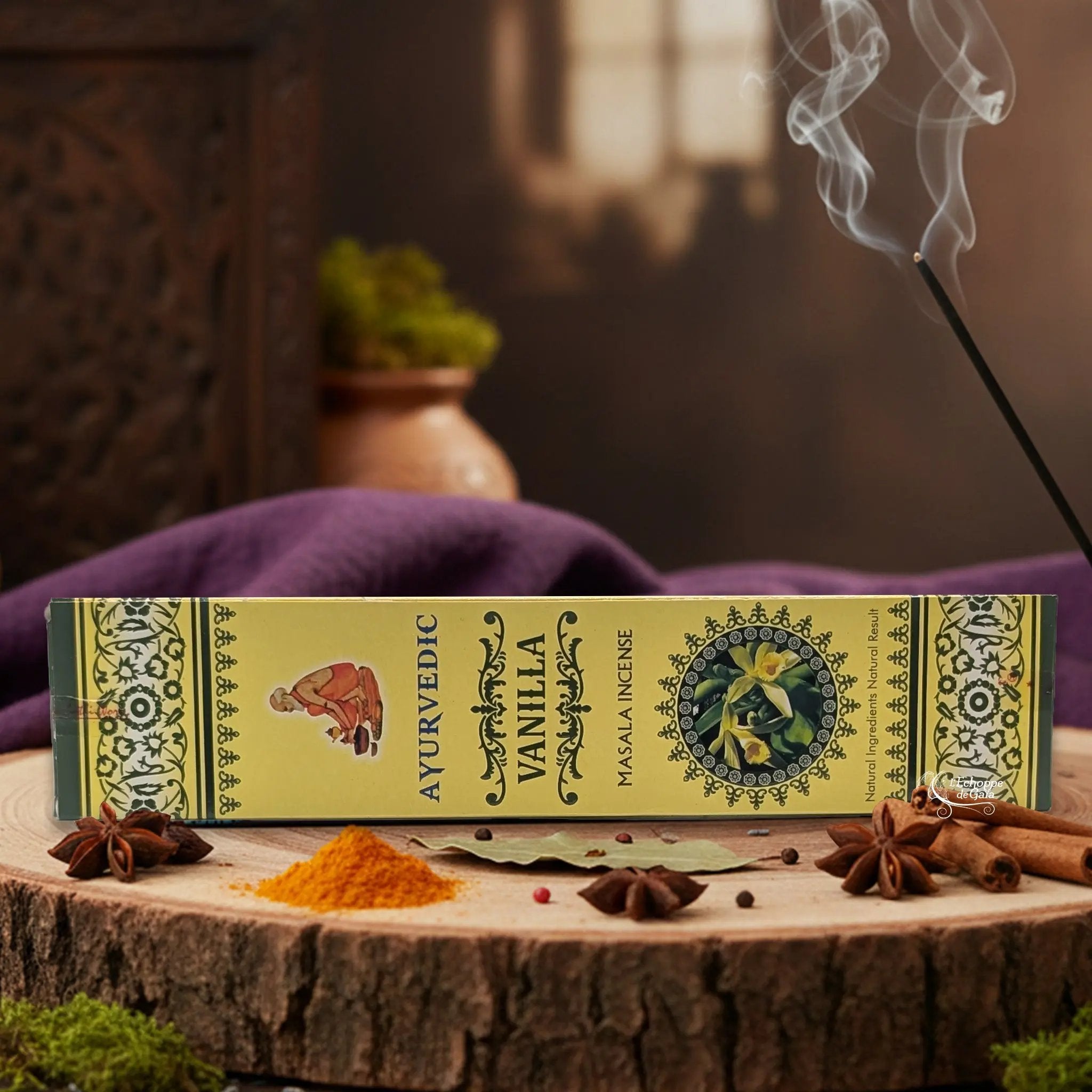 Boîte d'encens "Ayurvedic Vanilla Masala" sur une rondelle de bois, avec épices et encens fumant.