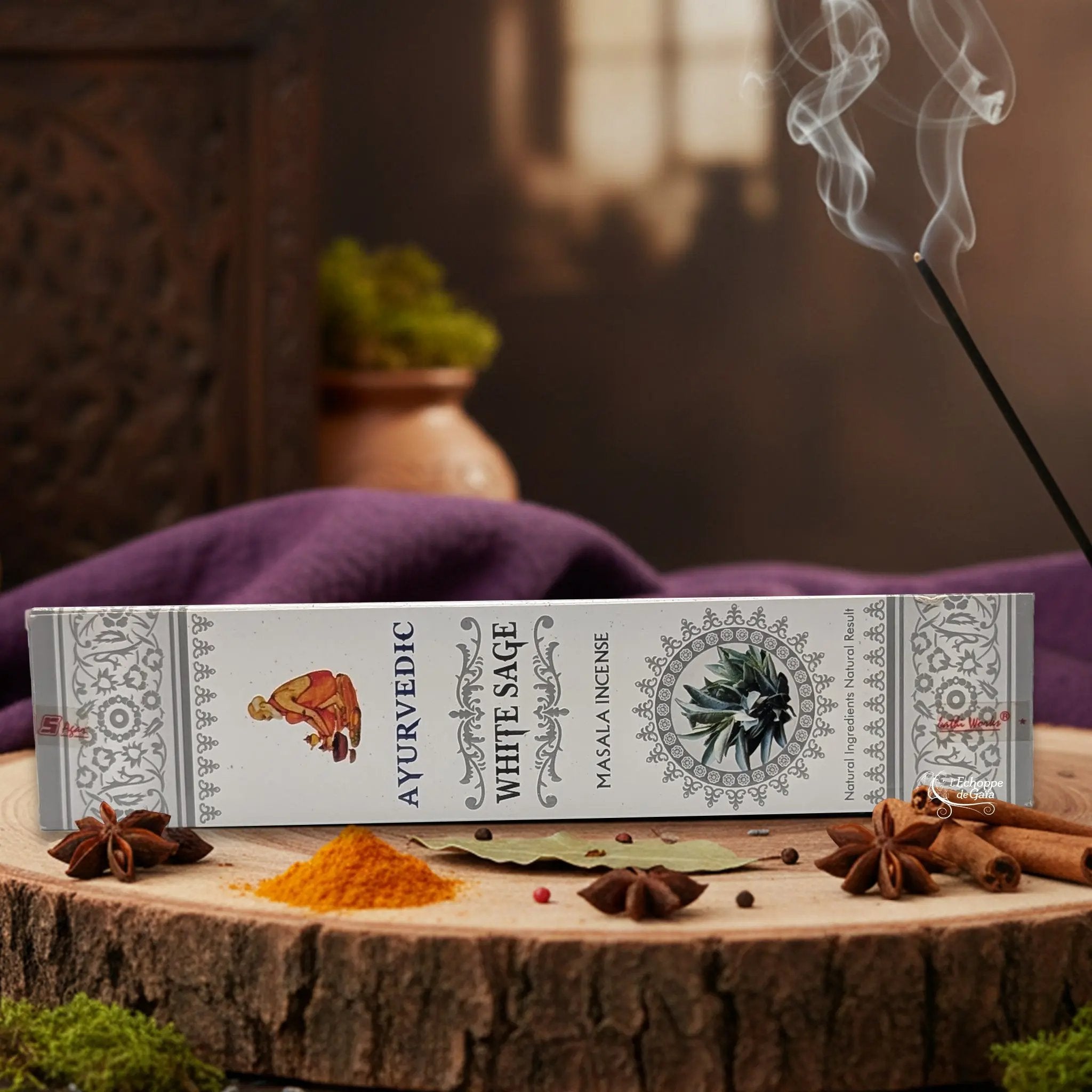 Boîte d'encens "Ayurvedic White Sage Masala" sur une rondelle de bois, avec épices et encens fumant.