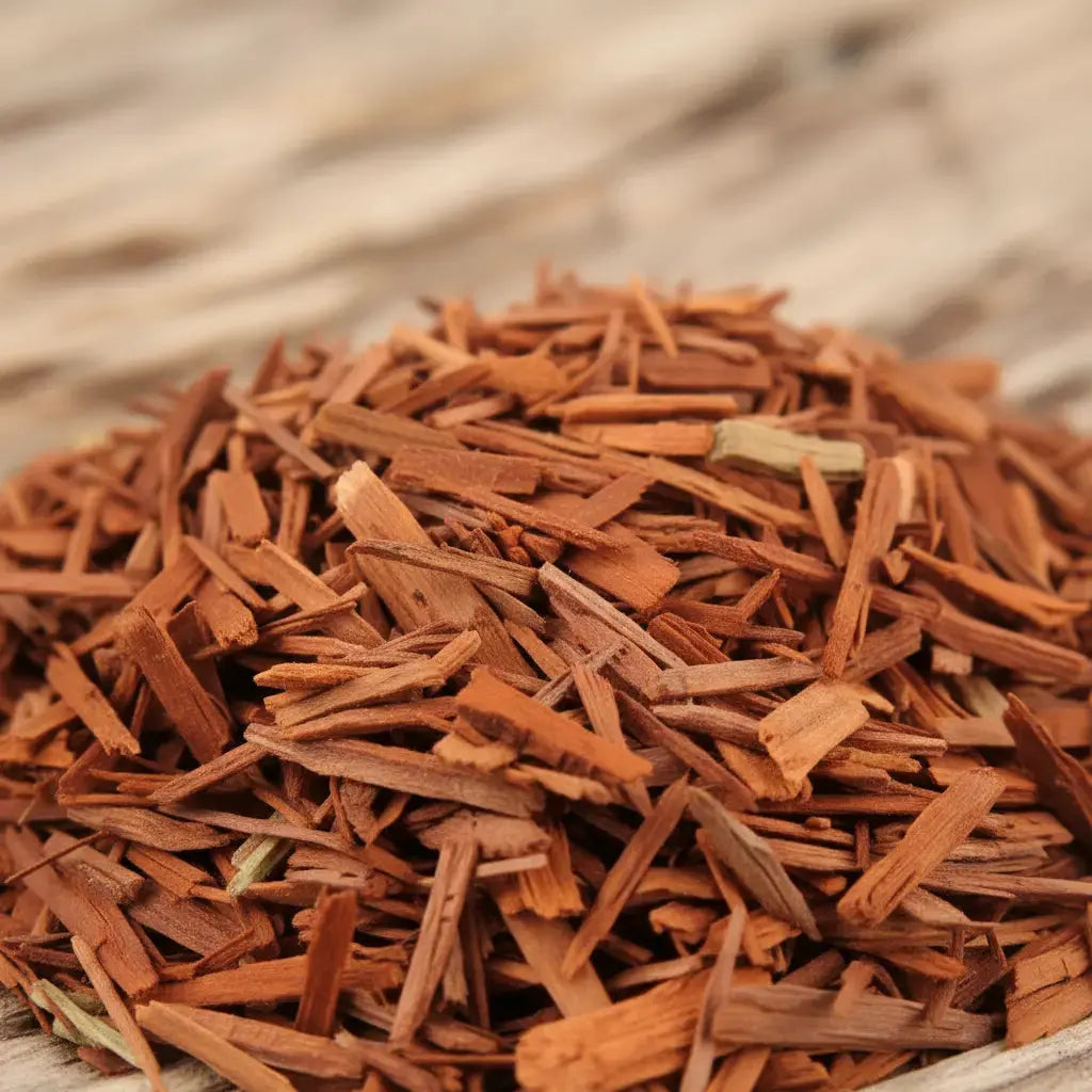 Bois de santal rouge pour fumigation, fins copeaux brun rouge en tas sur fond de bois clair.
