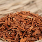 Bois de santal rouge pour fumigation, fins copeaux brun rouge en tas sur fond de bois clair.