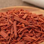 Bois de santal rouge pour fumigation, copeaux rouge-orangé en gros plan sur support en bois.