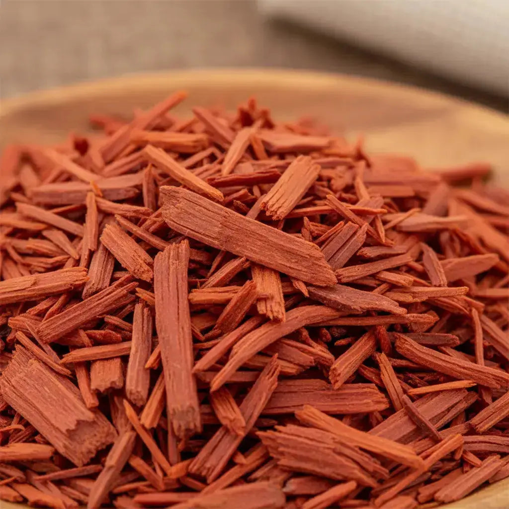 Bois de santal rouge pour fumigation, copeaux rouge-orangé en gros plan sur support en bois.