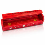 Boîte porte-encens en bois rouge entrouverte, décorée de lunes, d'étoiles et d'un soleil argentés, révélant deux petites coupelles en laiton à l'intérieur, sur fond blanc.