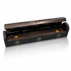 Boîte porte-encens en bois noir entrouverte, décorée de trois symboles Om dorés, révélant deux petites coupelles en laiton à l'intérieur, sur fond blanc.