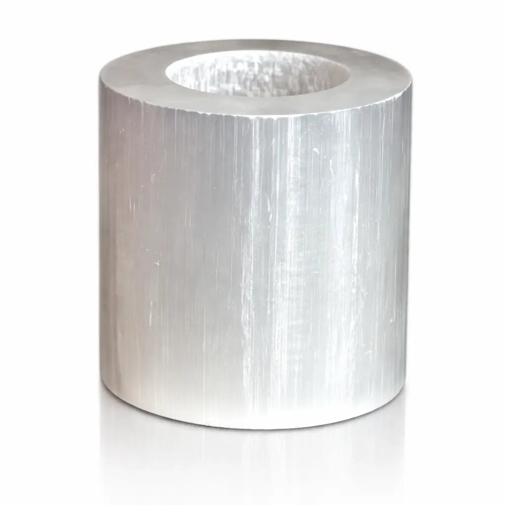 Un bougeoir en sélénite de forme cylindrique parfaite, présentant une surface polie aux reflets satinés et nacrés caractéristiques de la pierre, avec un emplacement central pour une bougie.