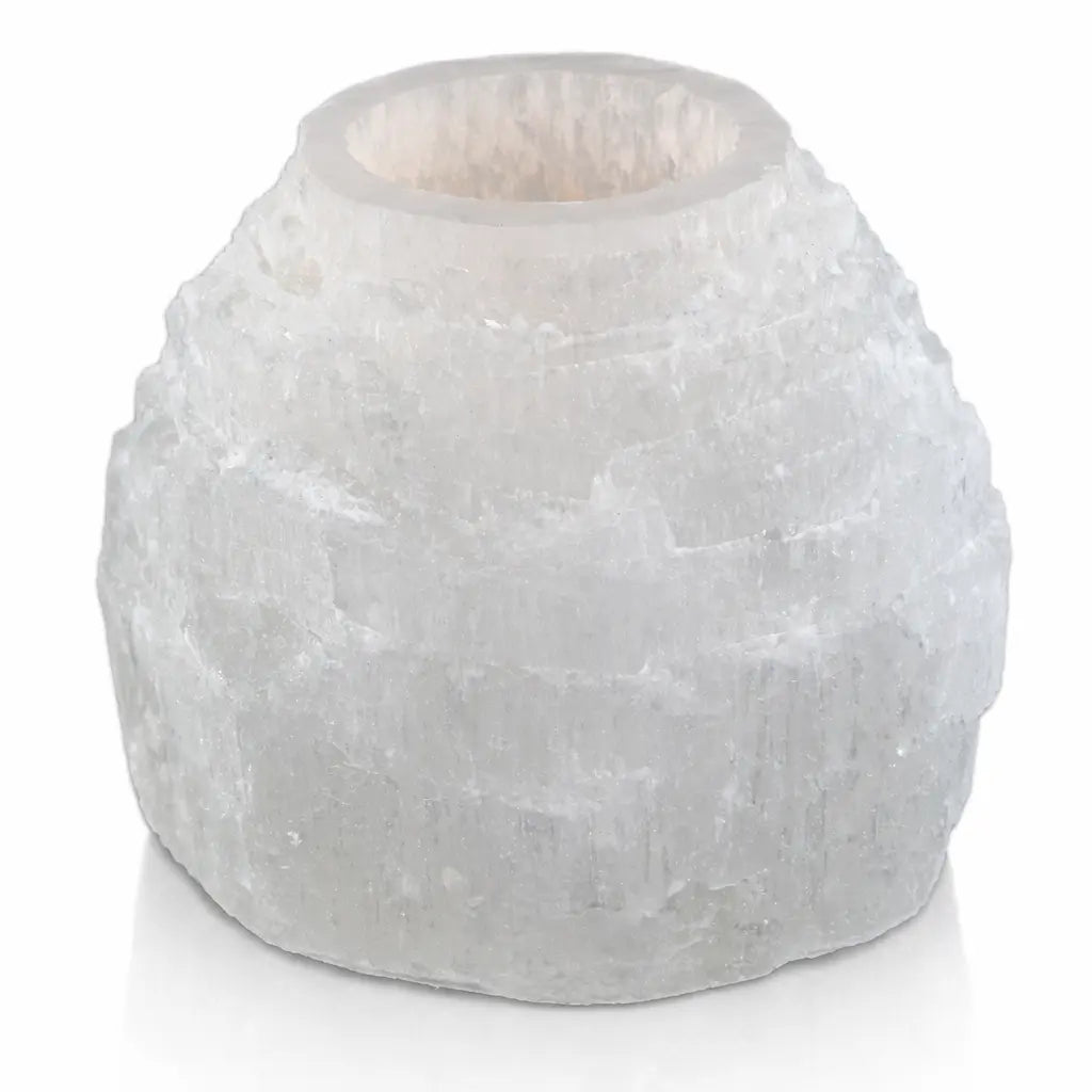 Un bougeoir en sélénite brute taillé en forme de dôme ou de "montagne", laissant apparaître ses fibres cristallines blanches et satinées, avec un réceptacle poli au sommet pour une bougie chauffe-plat.