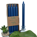 Bougies chandelles “PURE – Natural Wax” : lot de 4 bougies bleu foncé (dans étui carton), avec une chandelle bleue présentée à côté dans un bougeoir en verre, décorée de feuilles vertes et d’une petite succulente.
